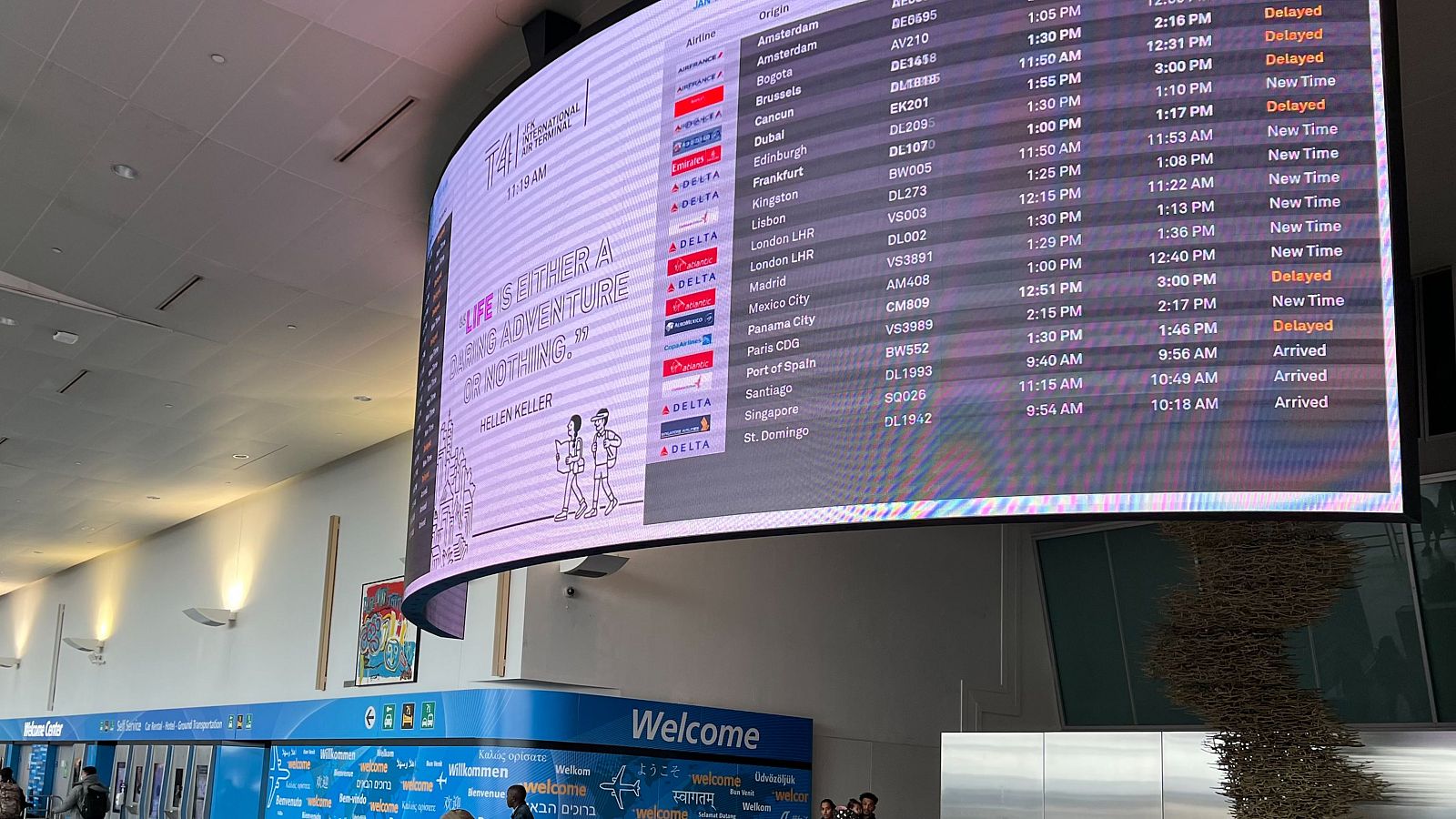 Fotografía de archivo del 11 de enero de 2023 que muestra a personas transportando sus equipajes por debajo de una pantalla de anuncio de vuelos en el Aeropuerto Internacional John F. Kennedy en Nueva York (EE.UU.).