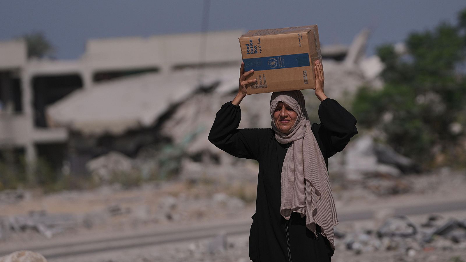 Una mujer de Gaza lleva una caja de comida del Programa Mundial de Alimentos