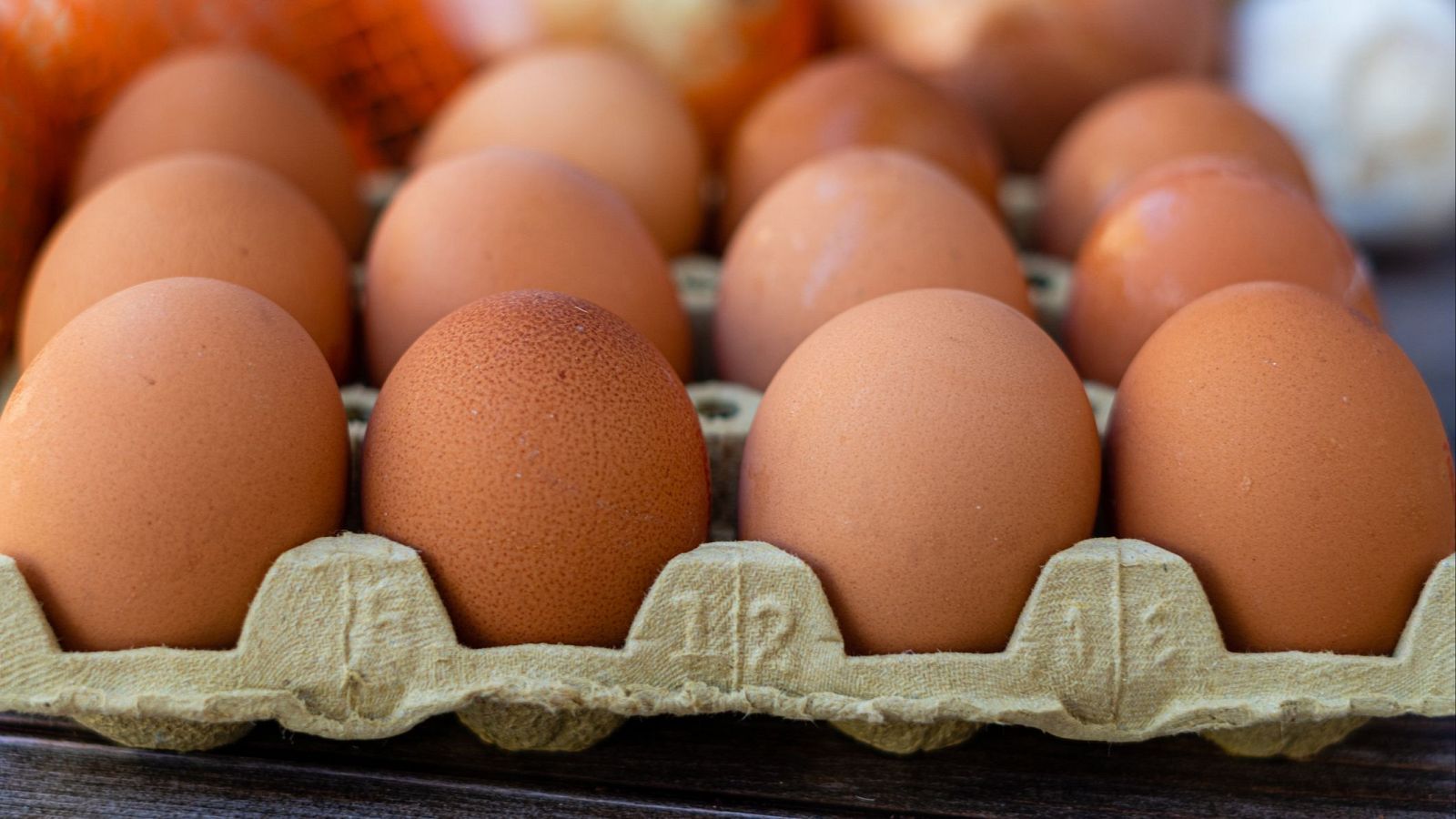 Huevos marrones en cartón gris, enfoque central, bordes desenfocados.  Textura rugosa del cartón.