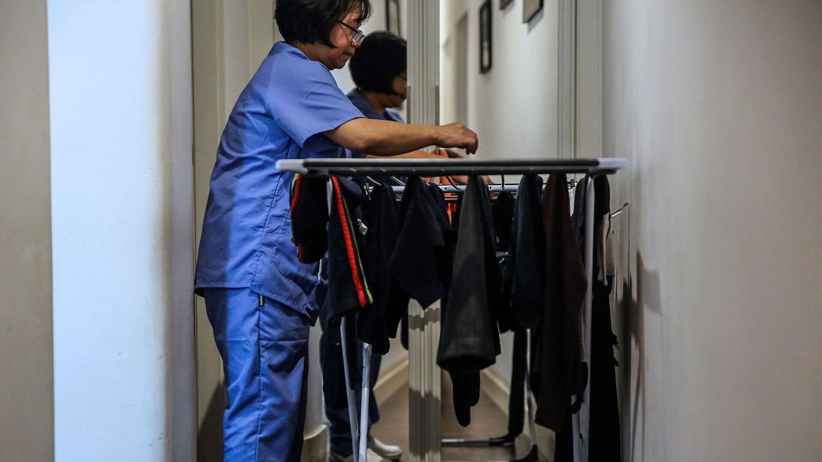 Una treballadora de la llar penjant roba a l'estenedor