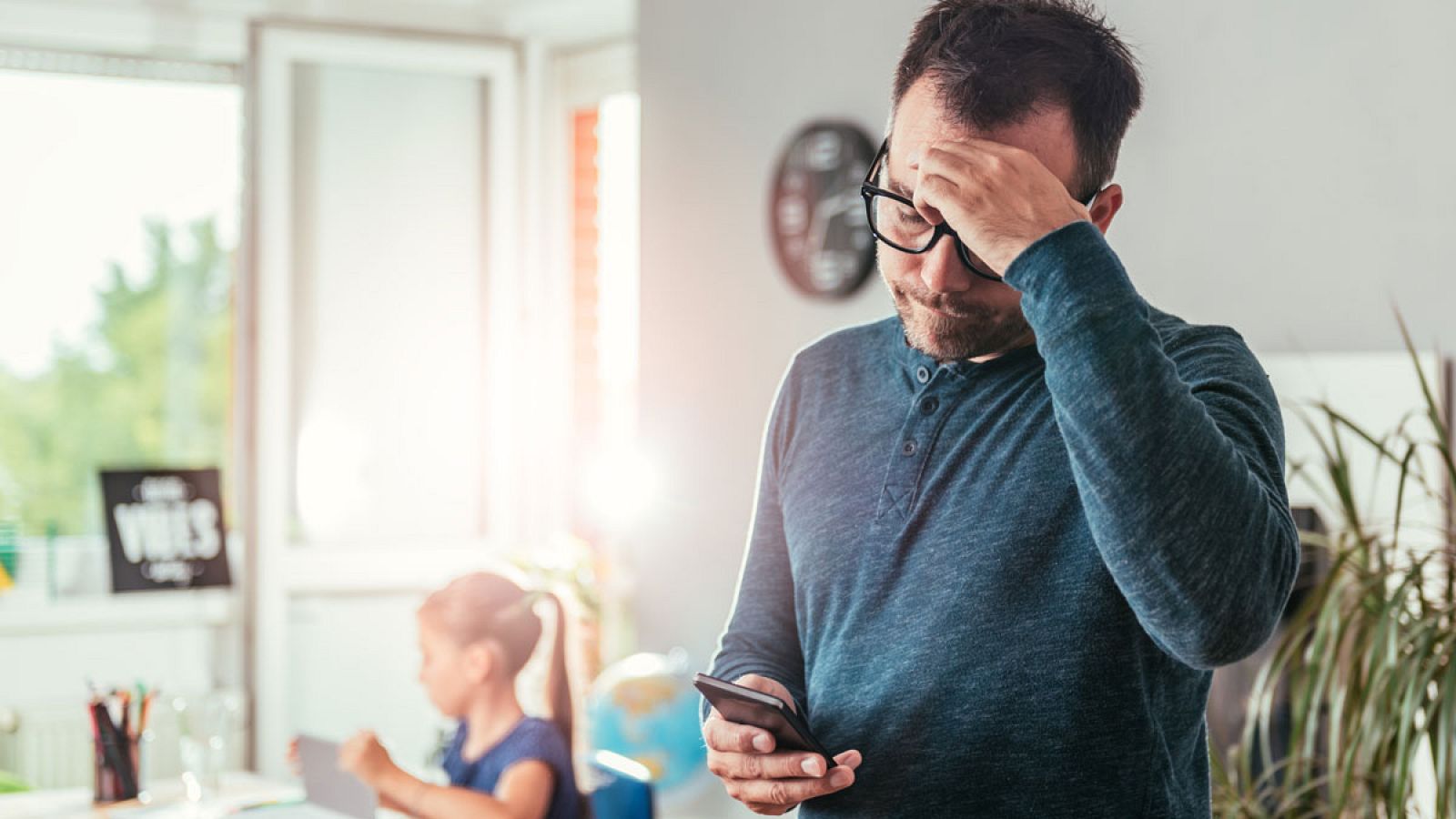 Un hombre consulta su móvil en su domicilio