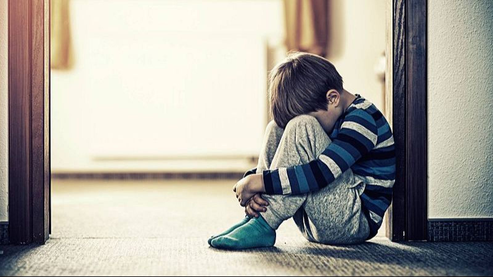 Un menor ajupit a terra a casa seva