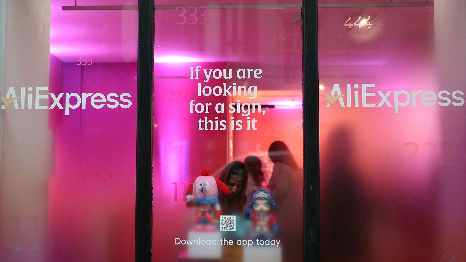 Clientes vistos a través de un escaparate en el interior de una tienda de AliExpress en Londres