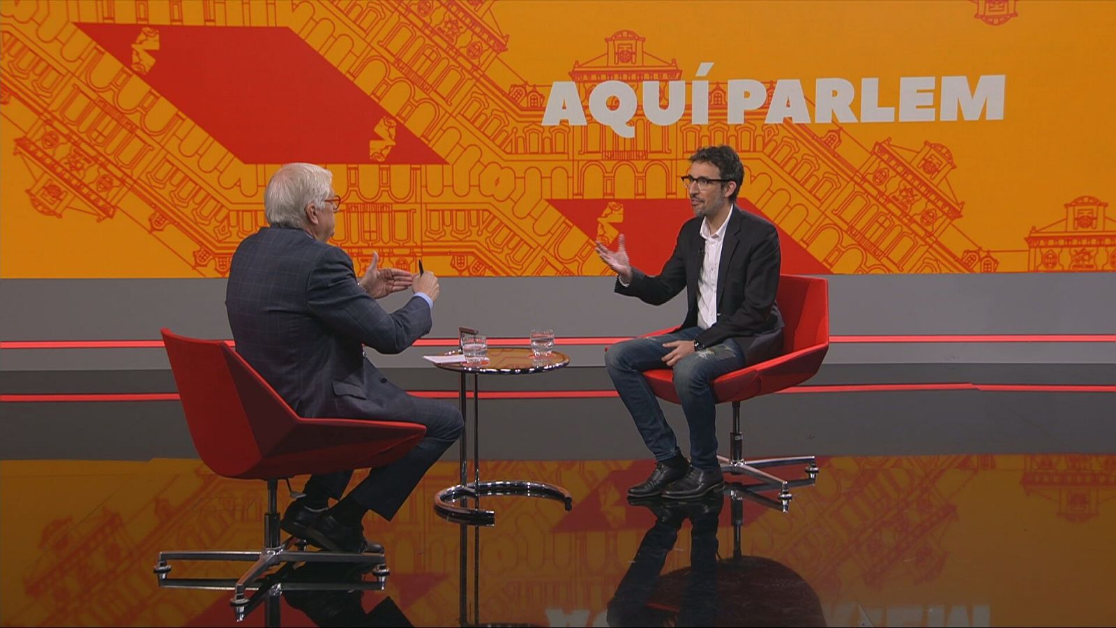 Lluís Falgàs i Joan Milián parlant, asseguts a unes cadires al plató del programa 'Aquí Parlem' de RTVE Catalunya