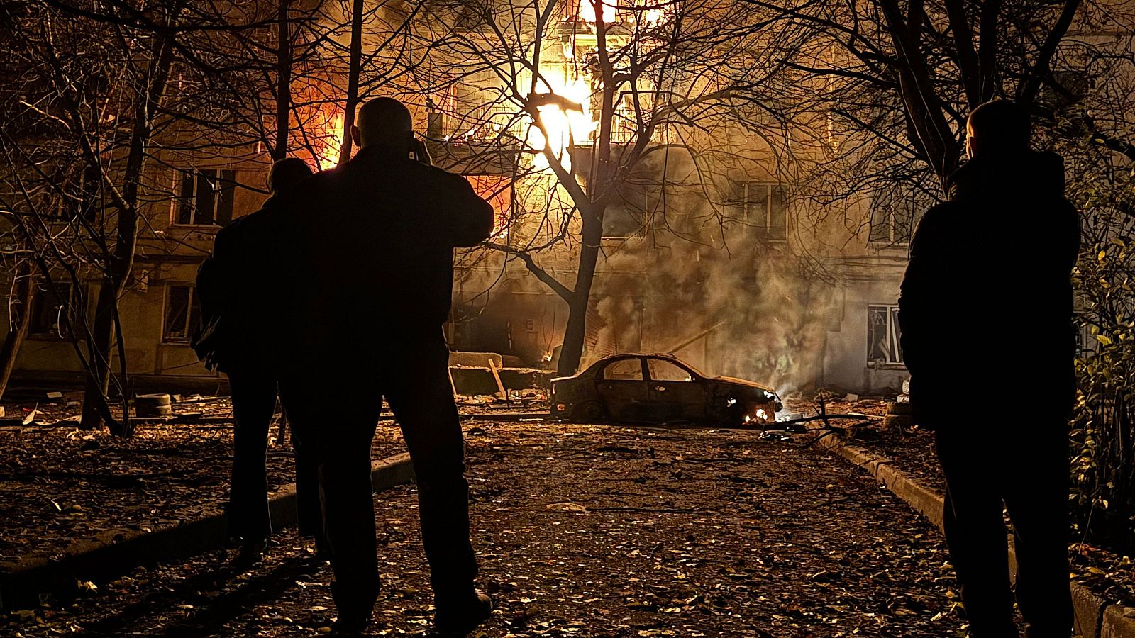 Vecinos contemplan un edificio en llamas en Zaporiyia después de un ataque ruso