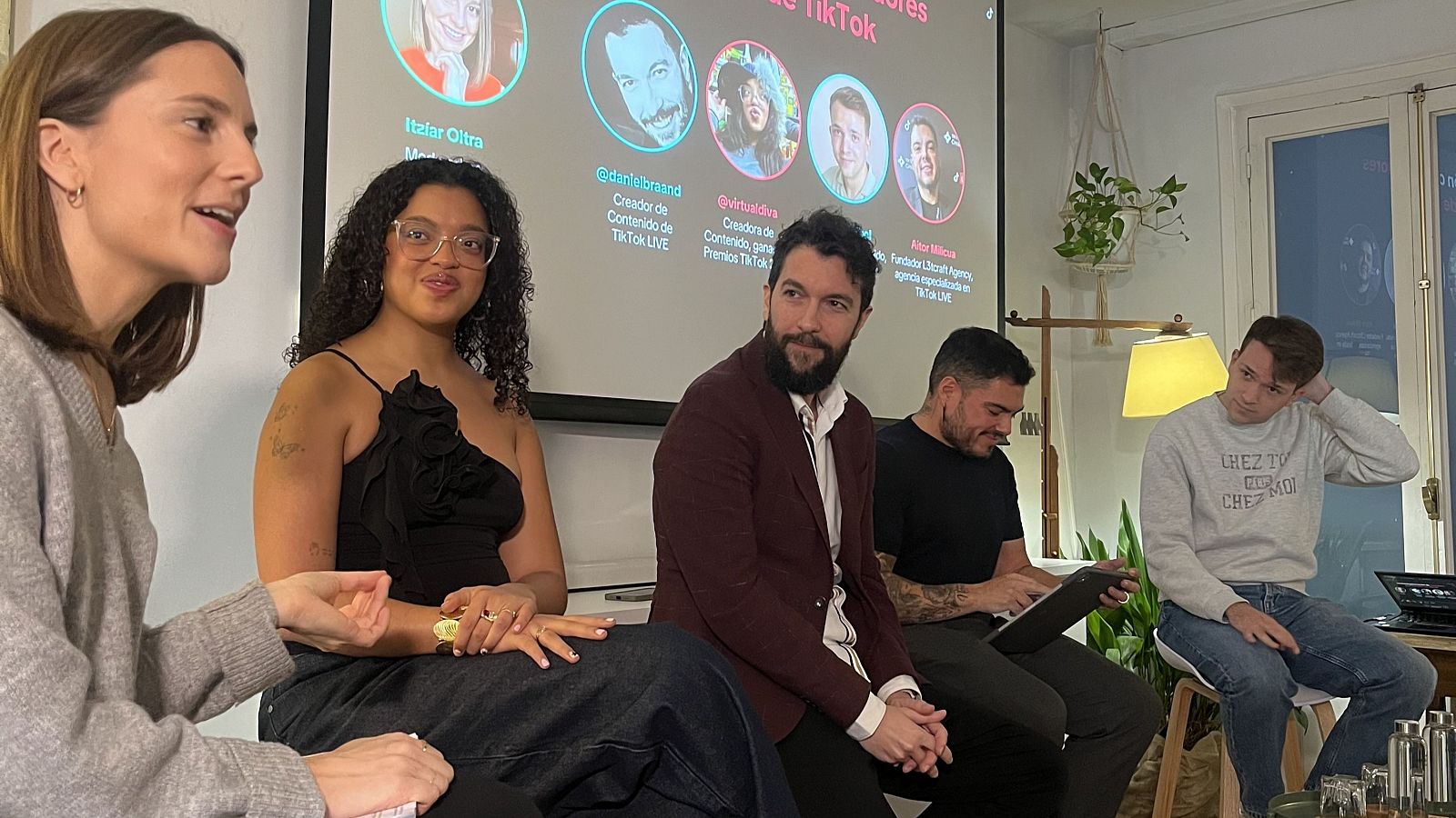 Un grupo de personas participa en un panel sobre TikTok, con una pantalla que muestra perfiles y nombres de usuarios de la plataforma.