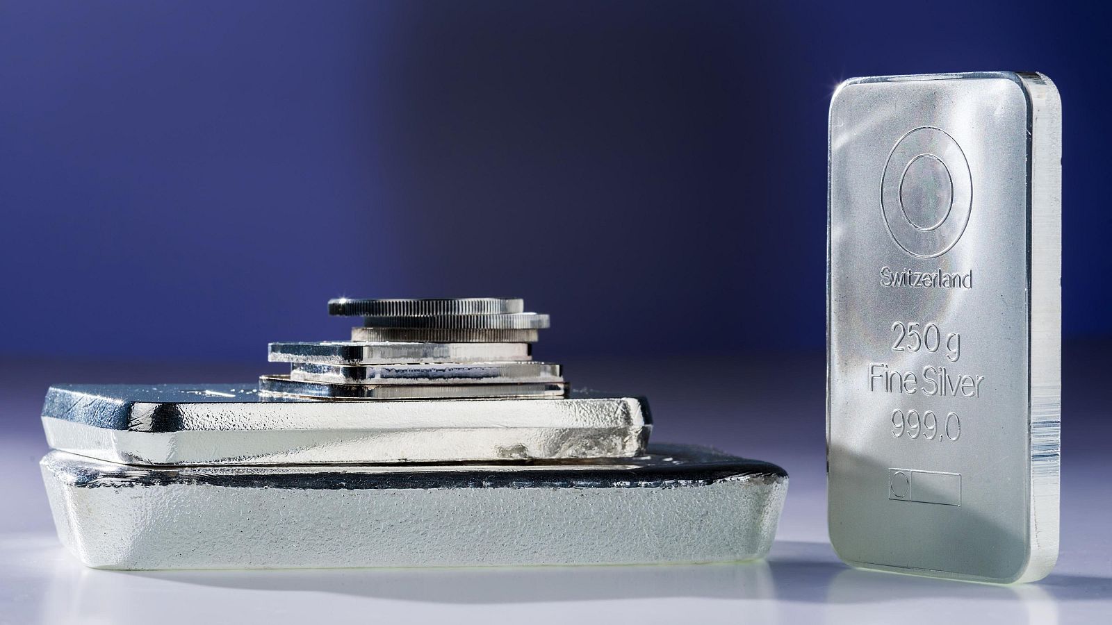 Onza de plata y monedas de plata sobre fondo azul