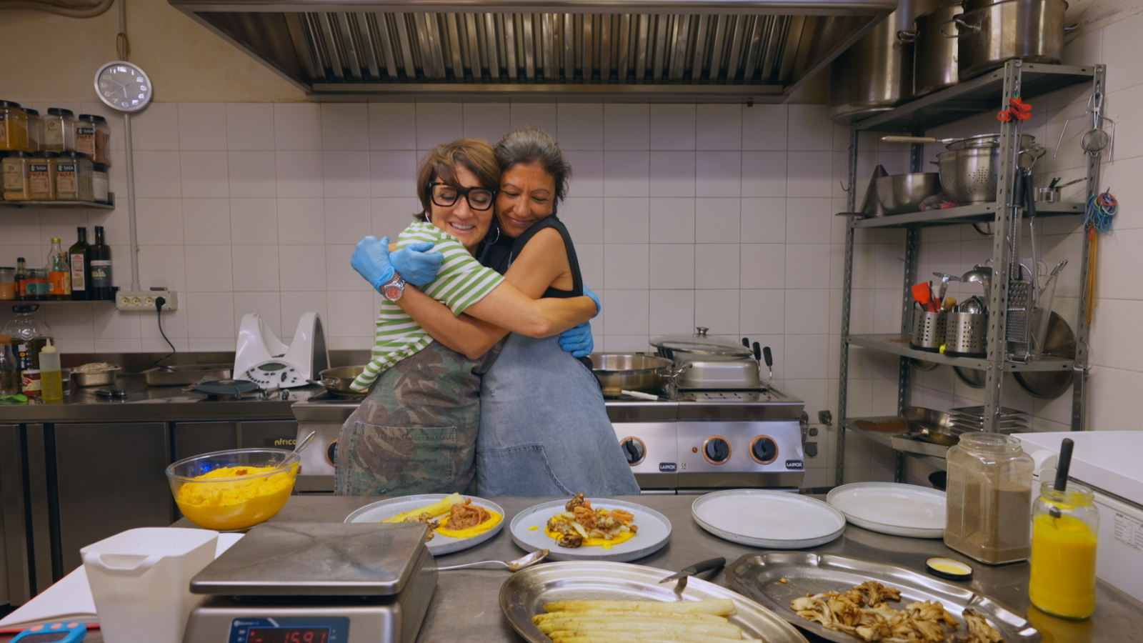 Sílvia Abril amb Viky Valls a una cuina preparant un plat de calamars amb ceba
