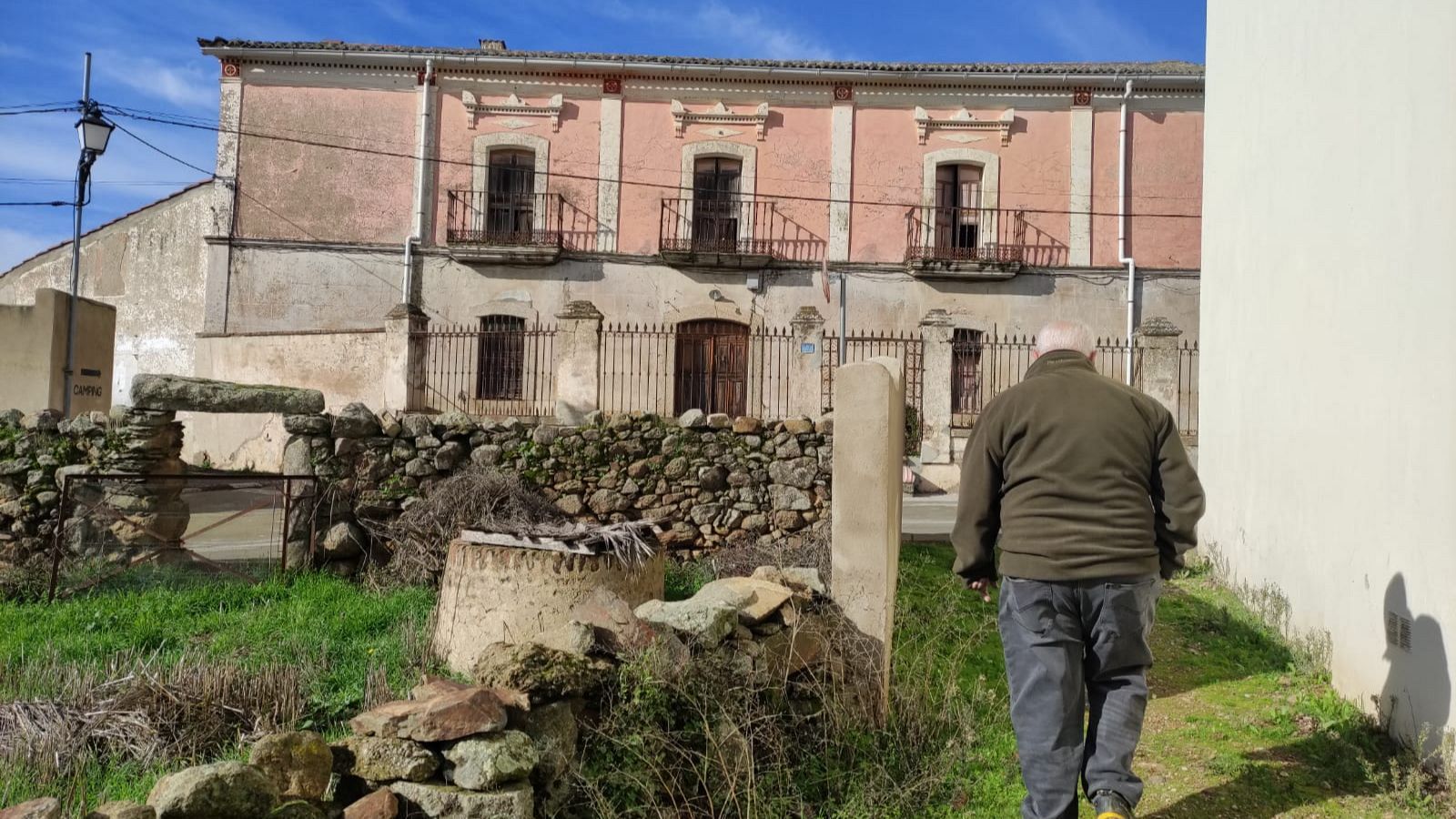El alcalde de Benquerencia, Alberto Buj, de espaldas ante un edificio del pueblo y que está pendiente de restaurar.