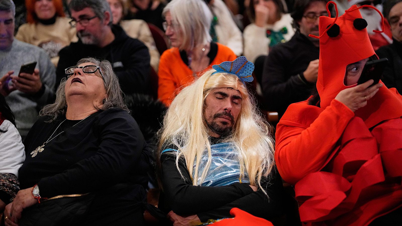 Lotería Navidad 2025: un grupo de asistentes al sorteo dormidos, detrás los activistas por Palestina