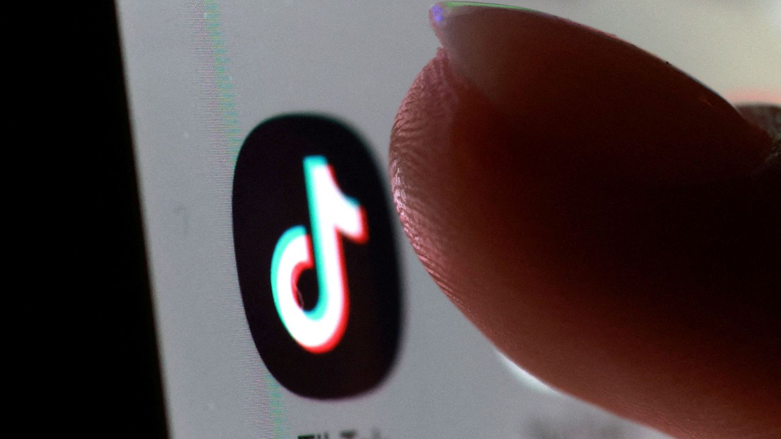 Detalle del dedo de una persona pulsando el logo de la aplicación TIKTOK
