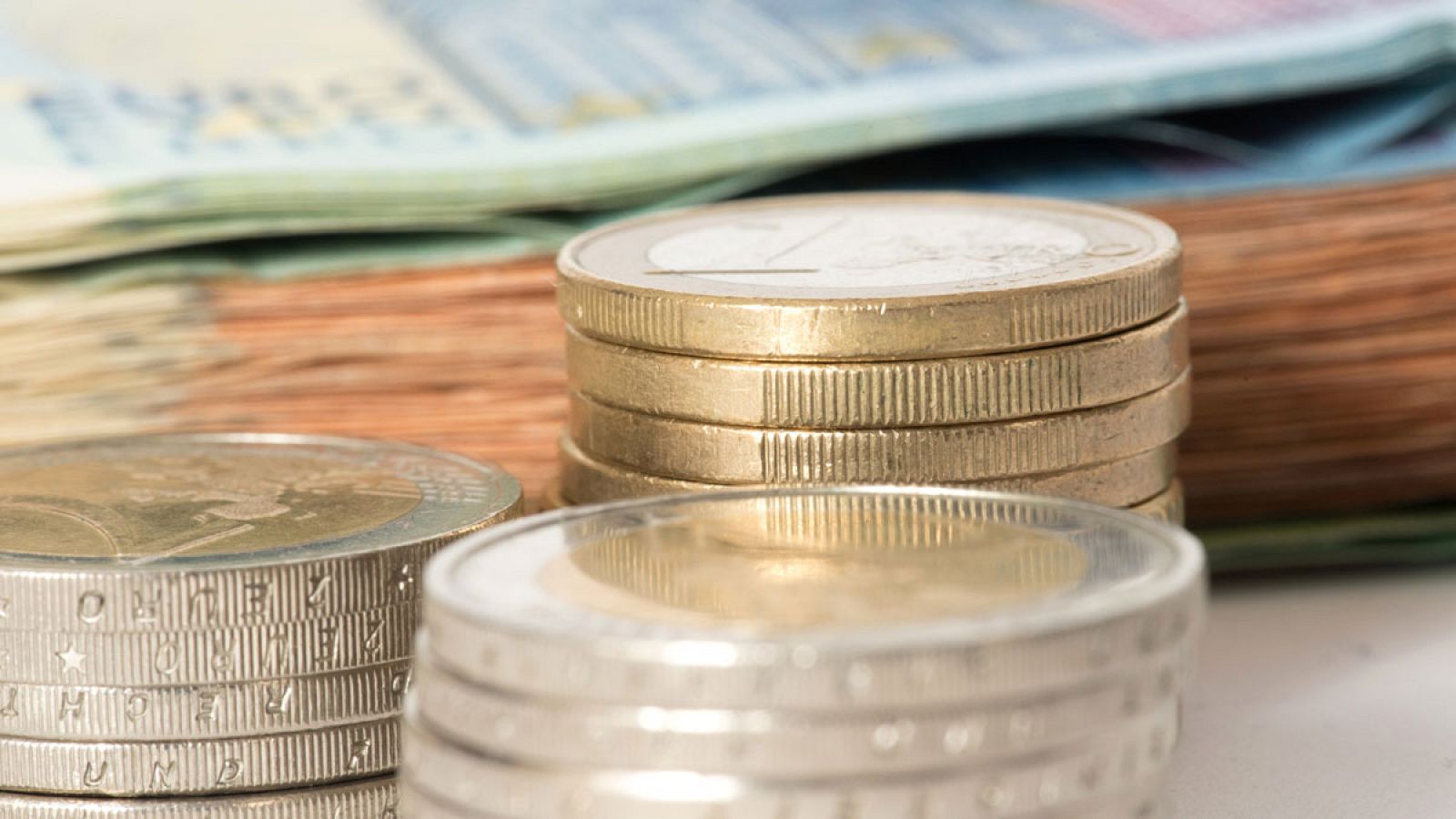 Monedas de euro apiladas sobre unos billetes de la misma moneda
