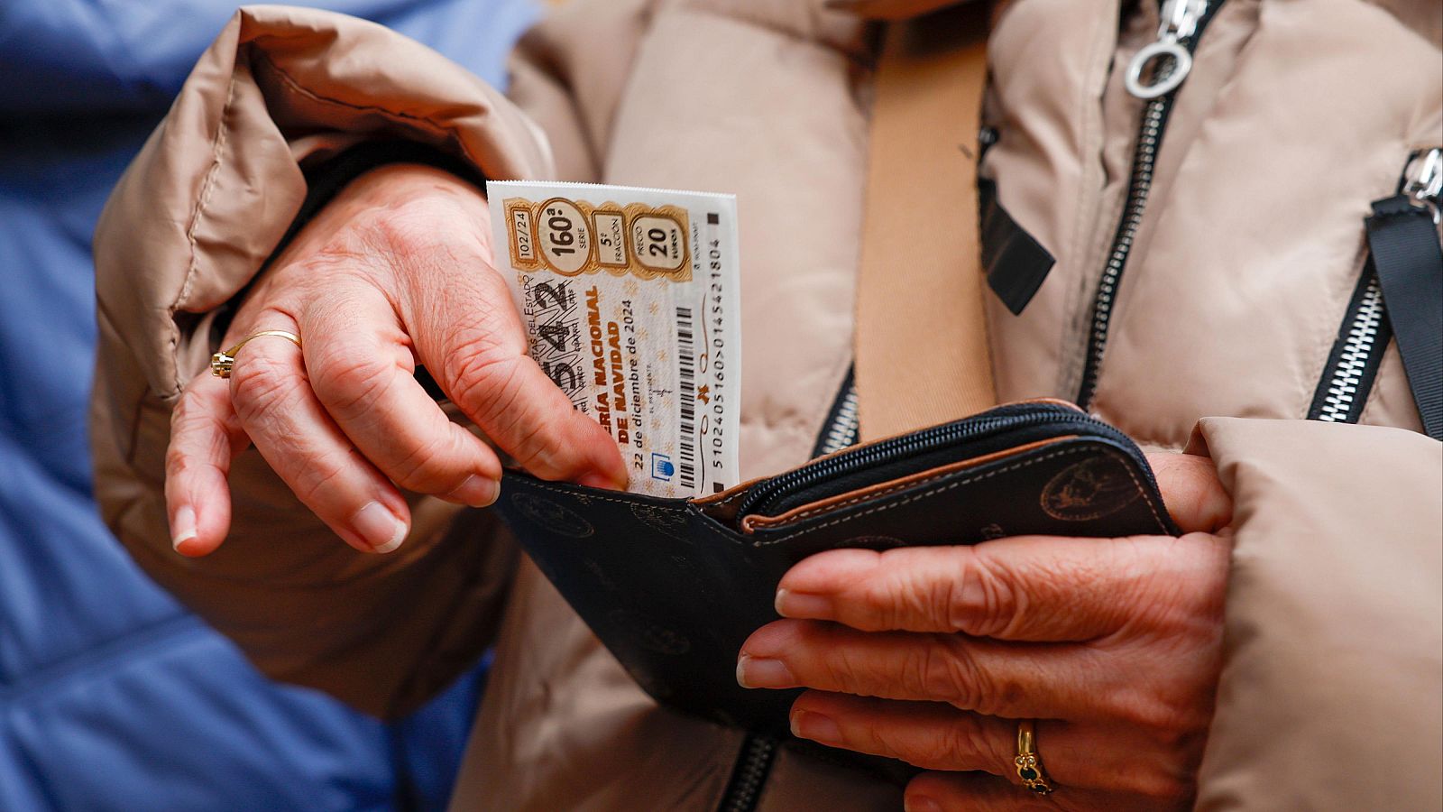 Una persona guarda un dècim de loteria en el seu moneder.
