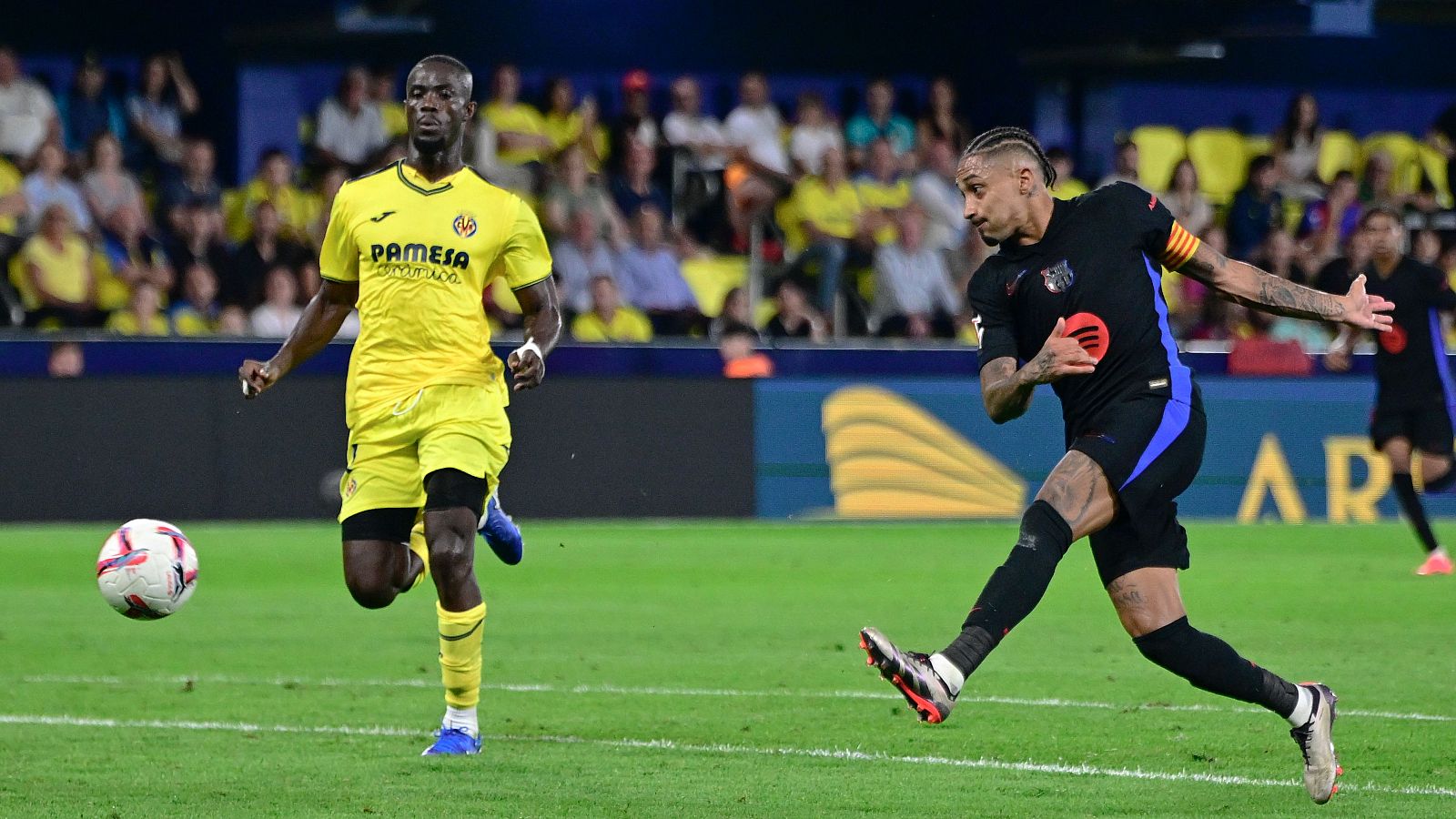 Raphinha (d) golpea el balón en el partido de Liga entre el Villarreal y el Barcelona disputado en el estadio de La Cerámica el año pasado