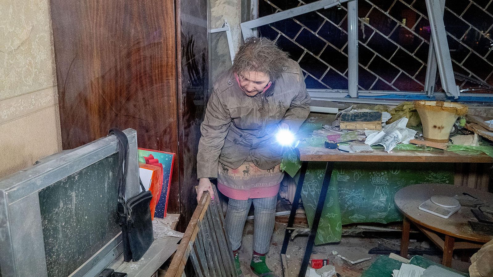 Una mujer barre los cristales rotos de las ventanas tras un ataque aéreo ruso en Járkov, Ucrania, el viernes 26 de diciembre