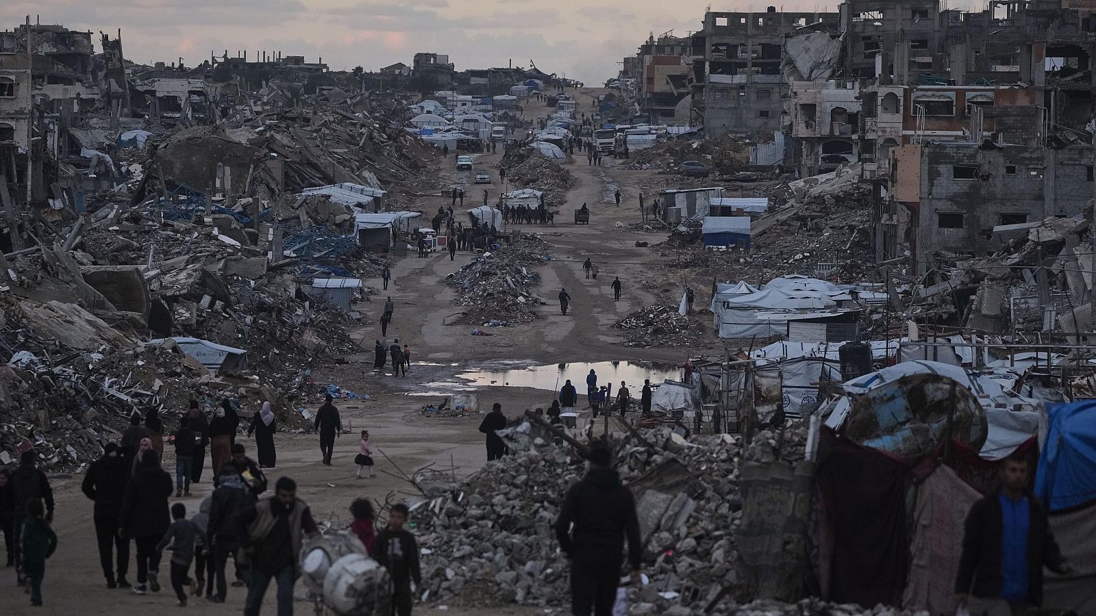 Palestinos caminan junto a edificios destruidos en el norte de la Franja de Gaza, ayer dos de enero.
