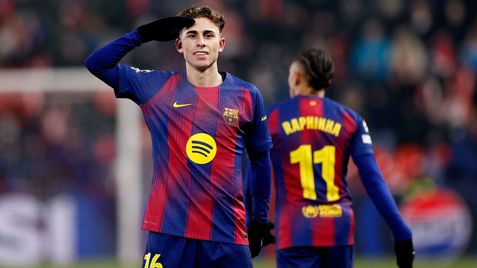 Promoción de la narración en directo de un partido de la Champions League, con los escudos de dos equipos de fútbol y el logo de la competición. El diseño incluye un recuadro con texto y el logo de una cadena de televisión.