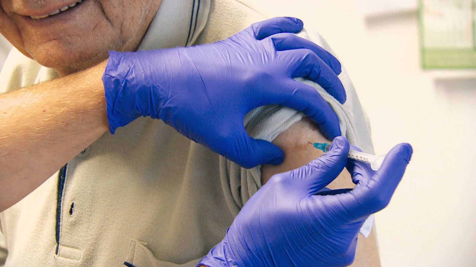 En un centro de salud, un profesional sanitario inyecta una vacuna en el brazo de un hombre. Se aprecia la jeringa y la aguja en el momento de la vacunación, mientras el paciente viste una camisa clara.