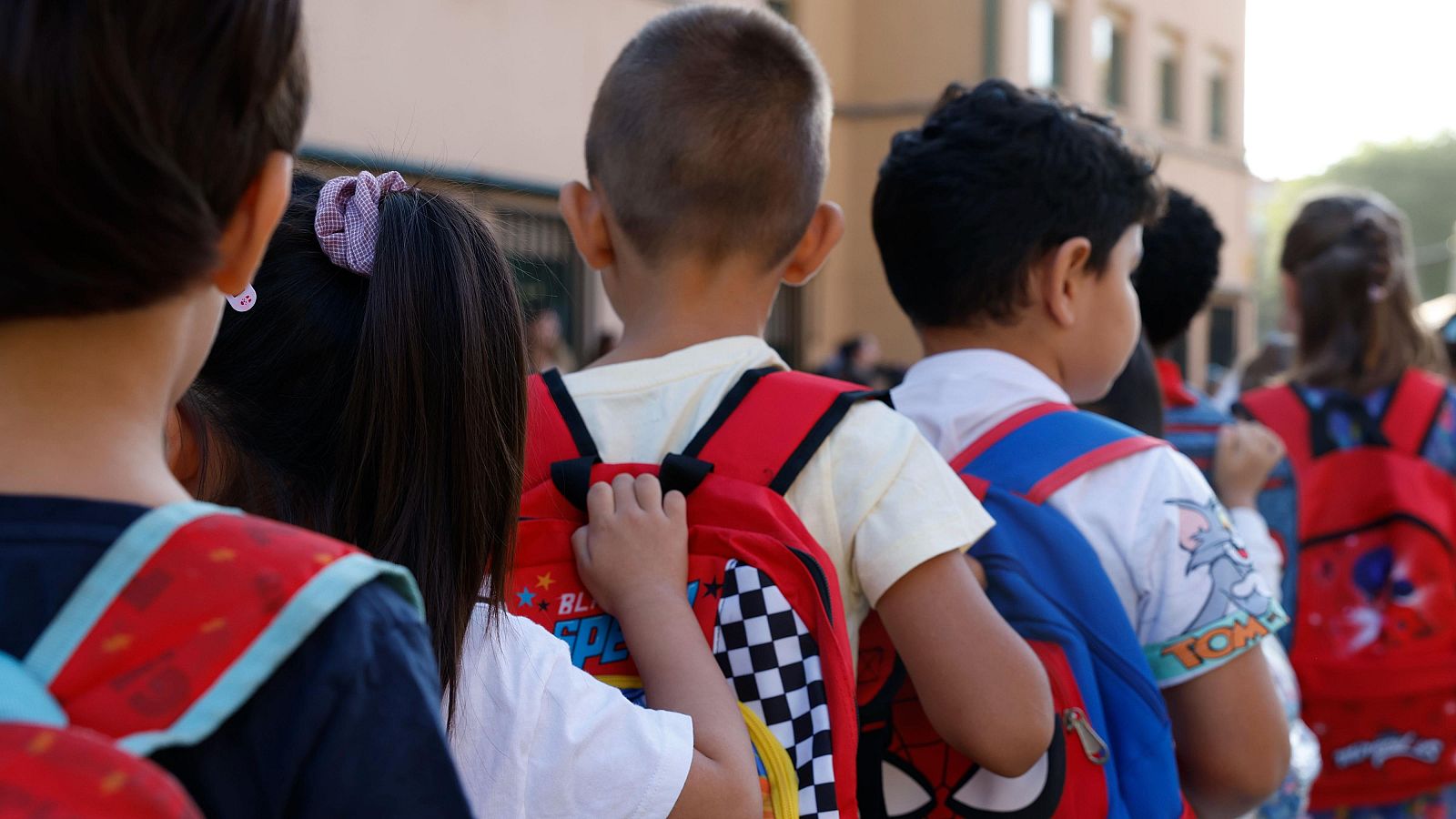 Uno niños en fila a la entrada del colegio en el comienzo de curso escolar de infantil y primaria