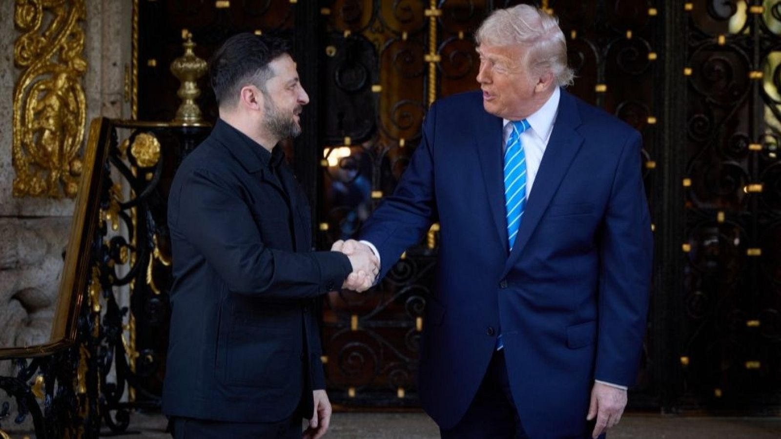 Volodímir Zelenski y Donald Trump se encuentran en una fotografía, uno a cada lado, con banderas de fondo. Zelenski viste de negro y Trump con traje oscuro, ambos mirando a la cámara.