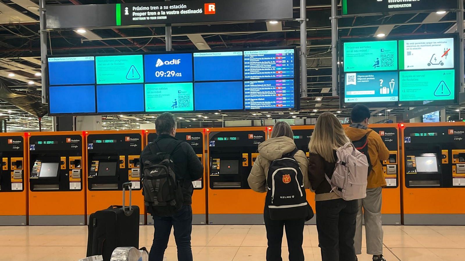 Usuarios de Rodalies de Renfe revisan las pantallas en la estación de Sants, en las que no aparece ningún tren.