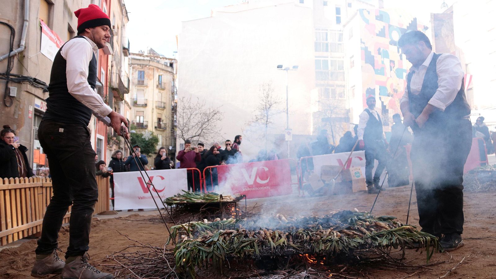 Dos homes retiren de les brases calçots per ser cuits a la Gran Festa de la Calçotada de Valls