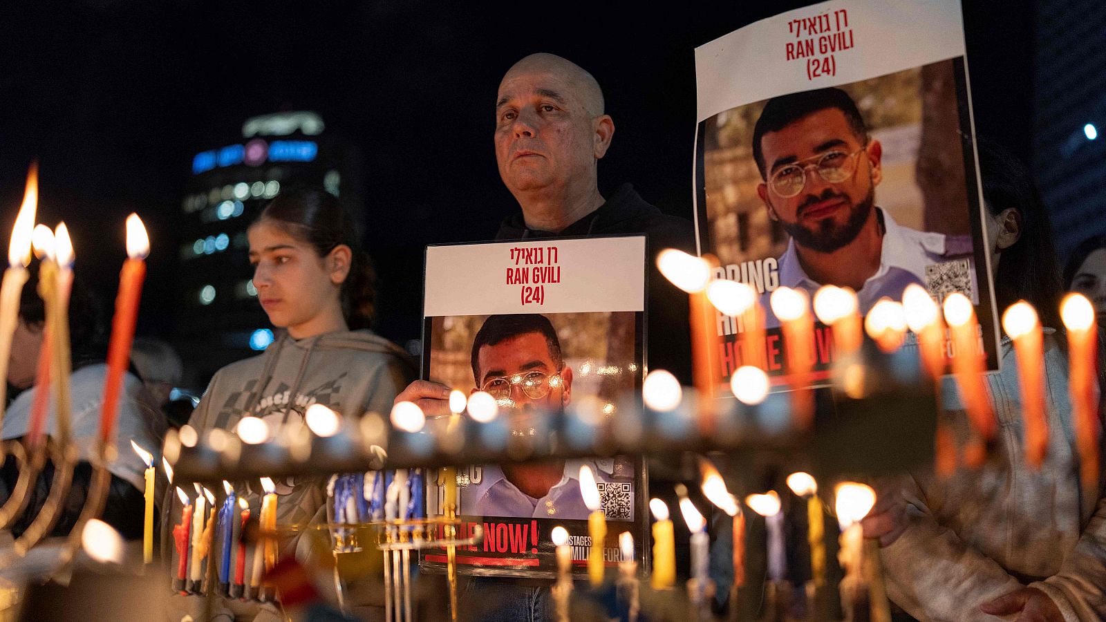 Una vigilia nocturna en Tel Aviv muestra velas encendidas y personas con carteles. Los carteles exhiben la foto de un joven de 24 años y mensajes en hebreo e inglés.