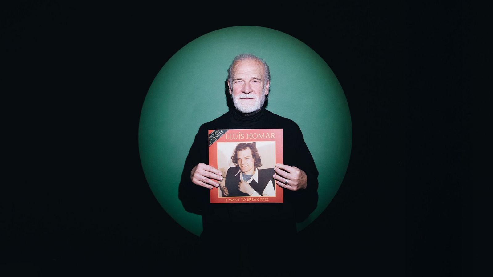 Un home gran, Lluís Homar, amb cabells blancs, sosté un disc amb la seva imatge de jove a la portada, amb un fons circular verd brillant.
