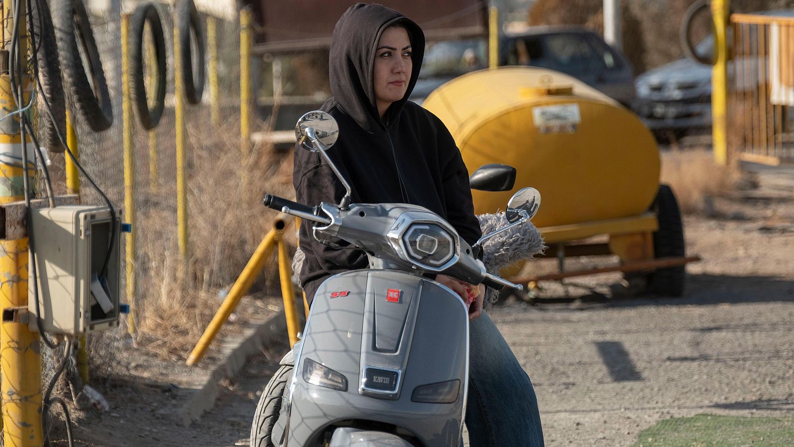 Una mujer, identificada como Fatemeh Moghaddas, posa sobre una motocicleta gris, vestida con una sudadera negra. La imagen fue capturada en un centro de entrenamiento de motocicletas.
