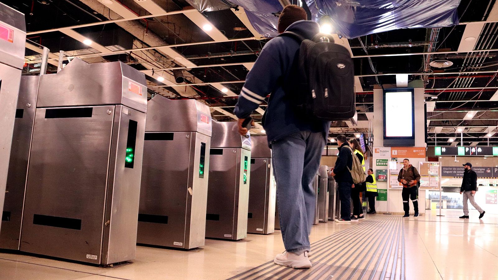 Un viatger de Rodalies a l'estació de Sants valida el seu bitllet (ACN | Gerard Escaich Folch)