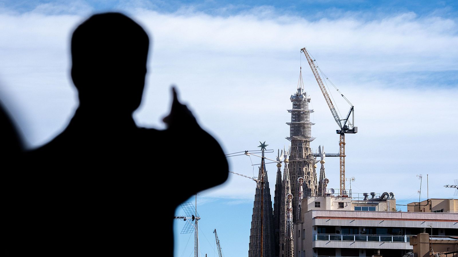 Una persona assenyala la Torre de Jesús, amb la grua acabant de col·lobar el braç superior