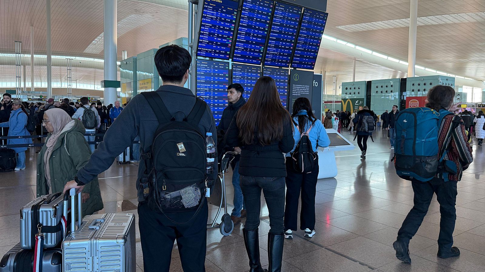 Usuaris consultant un panell informatiu a l’aeroport del Prat