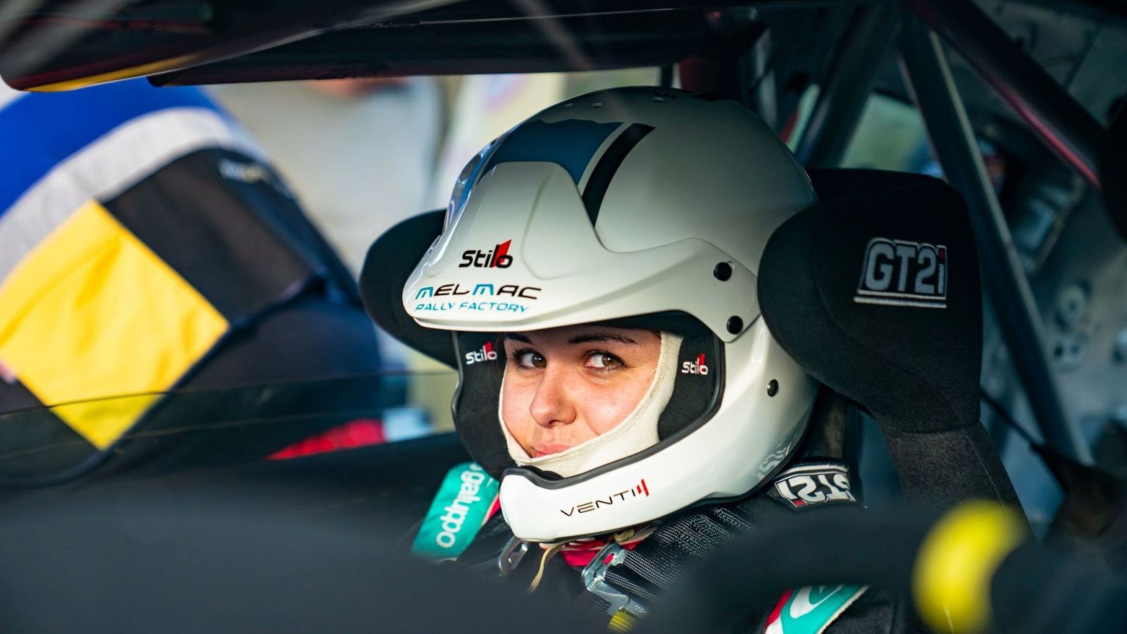 En la imagen se observa a una mujer con casco de automoción subida en un coche de rally