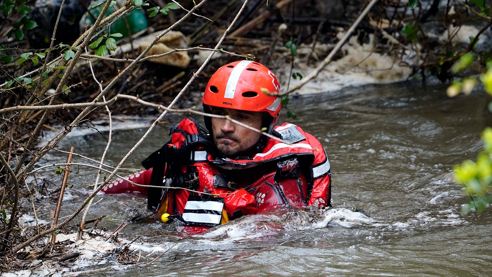 Un miembro de los servicios de rescate busca en el interior del agua a una mujer de 56 años que se precipitó al río Silvestre