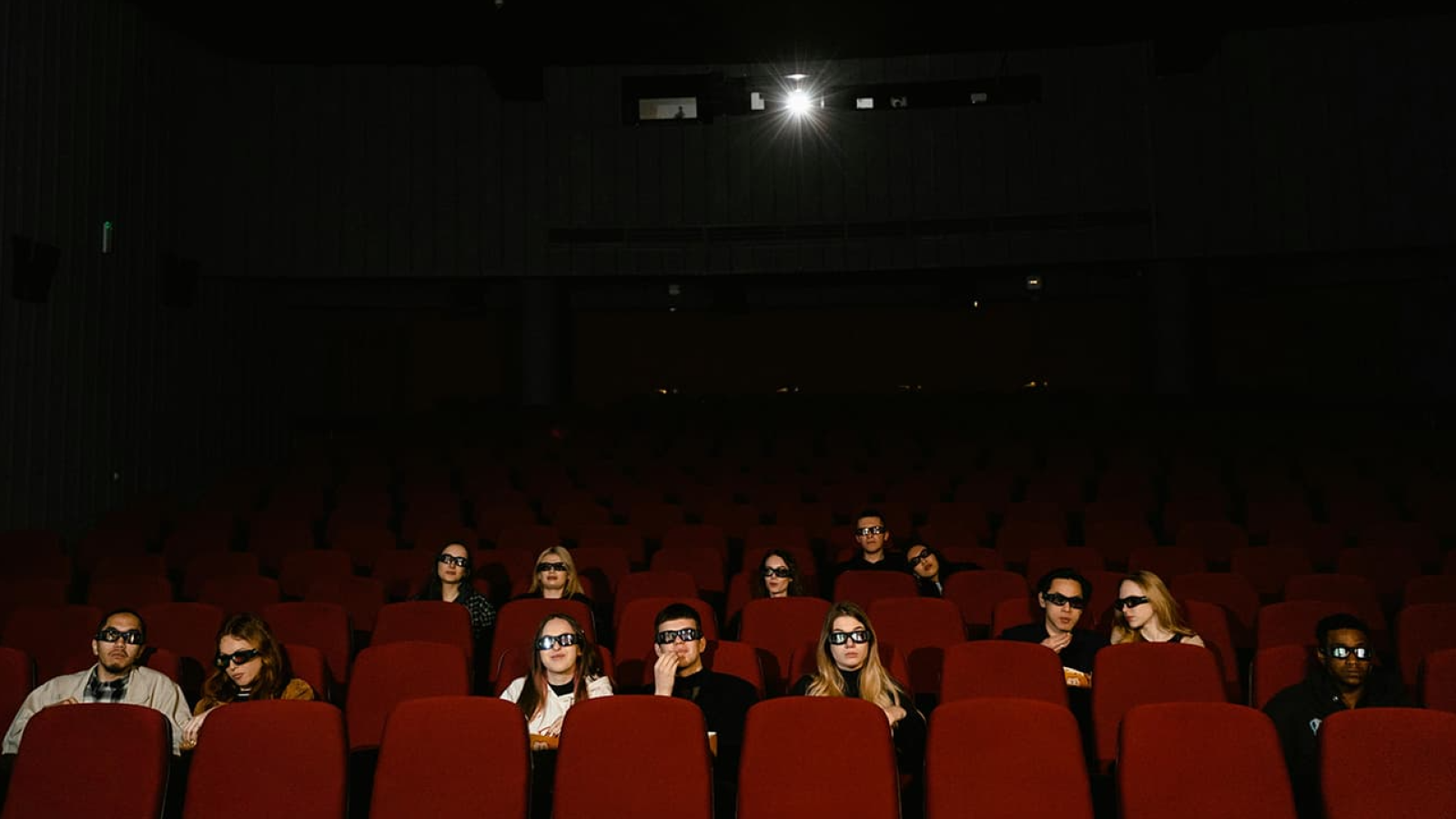 Una sala de cie con personas viendo una película con gafas 3D