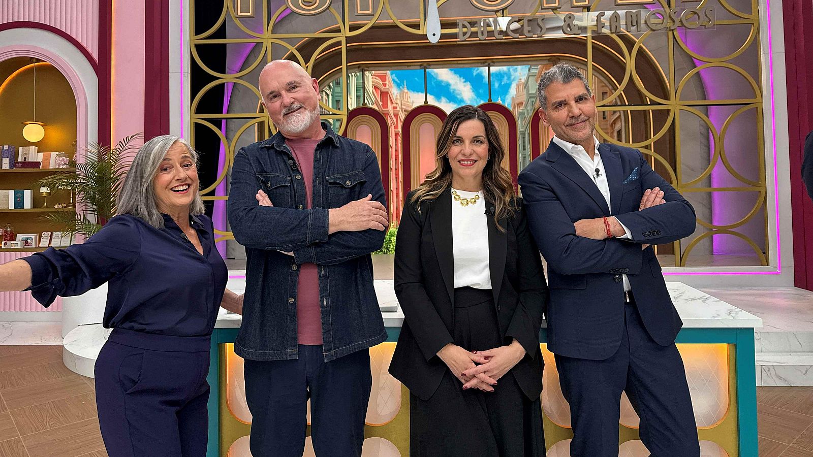 Cuatro individuos posan para una foto frente a un decorado que incluye elementos dorados y una imagen de una calle, con el rótulo "Dulces y Famosos".