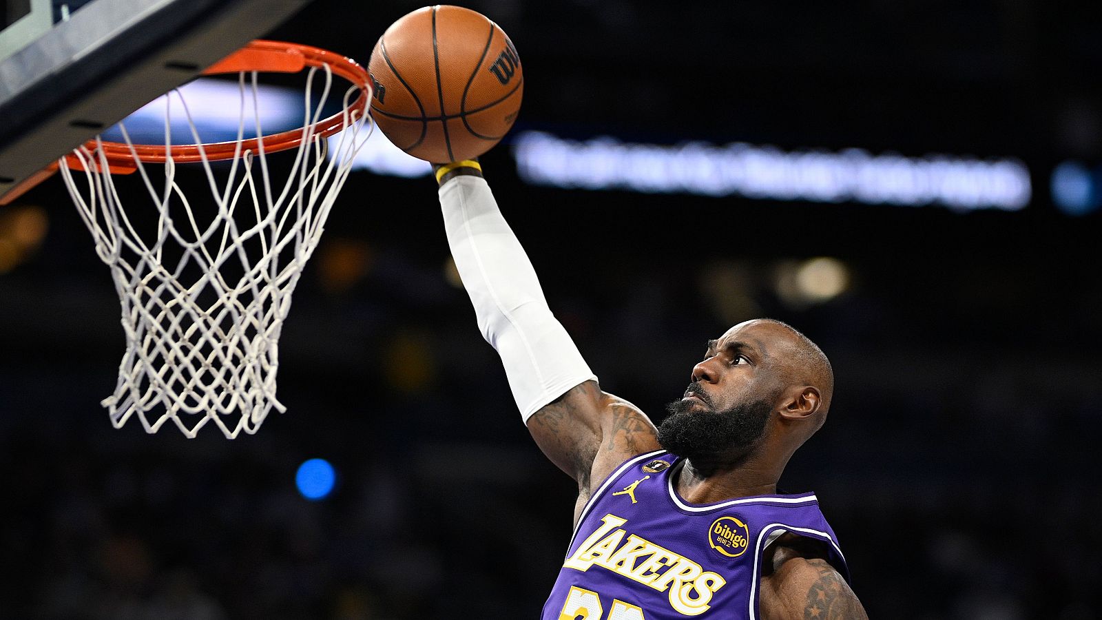 LeBron James, jugador de baloncesto, ejecuta una jugada ofensiva durante un partido, portando la camiseta de su equipo y con el balón en la mano cerca de la canasta.