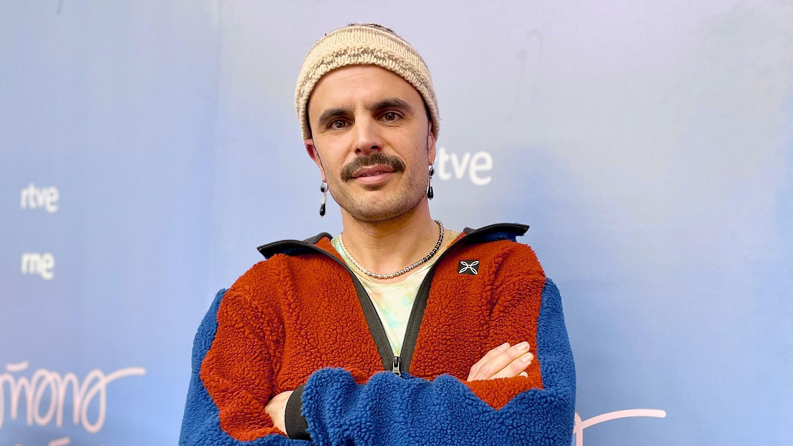 Rodrigo Cuevas, con gorro y chaqueta bicolor, posa en un plató con el logotipo de RTVE y parte del texto 'Mañana'.