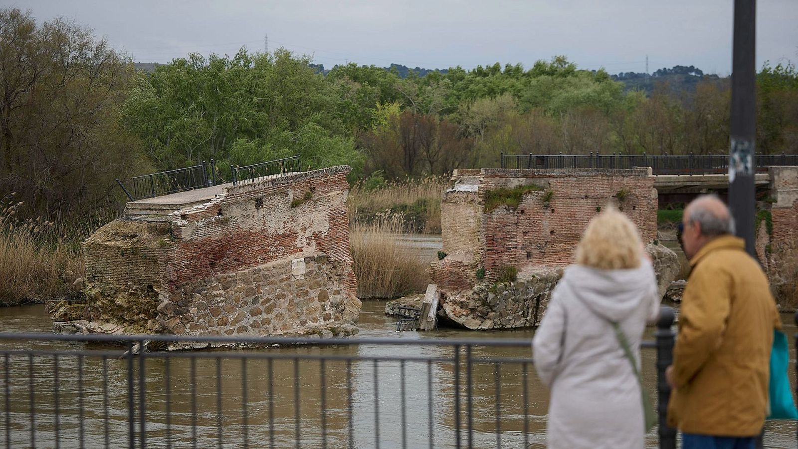 En la imagen se observa a dos personas contemplando el derrumbe del puente viejo de Talavera de la Reina