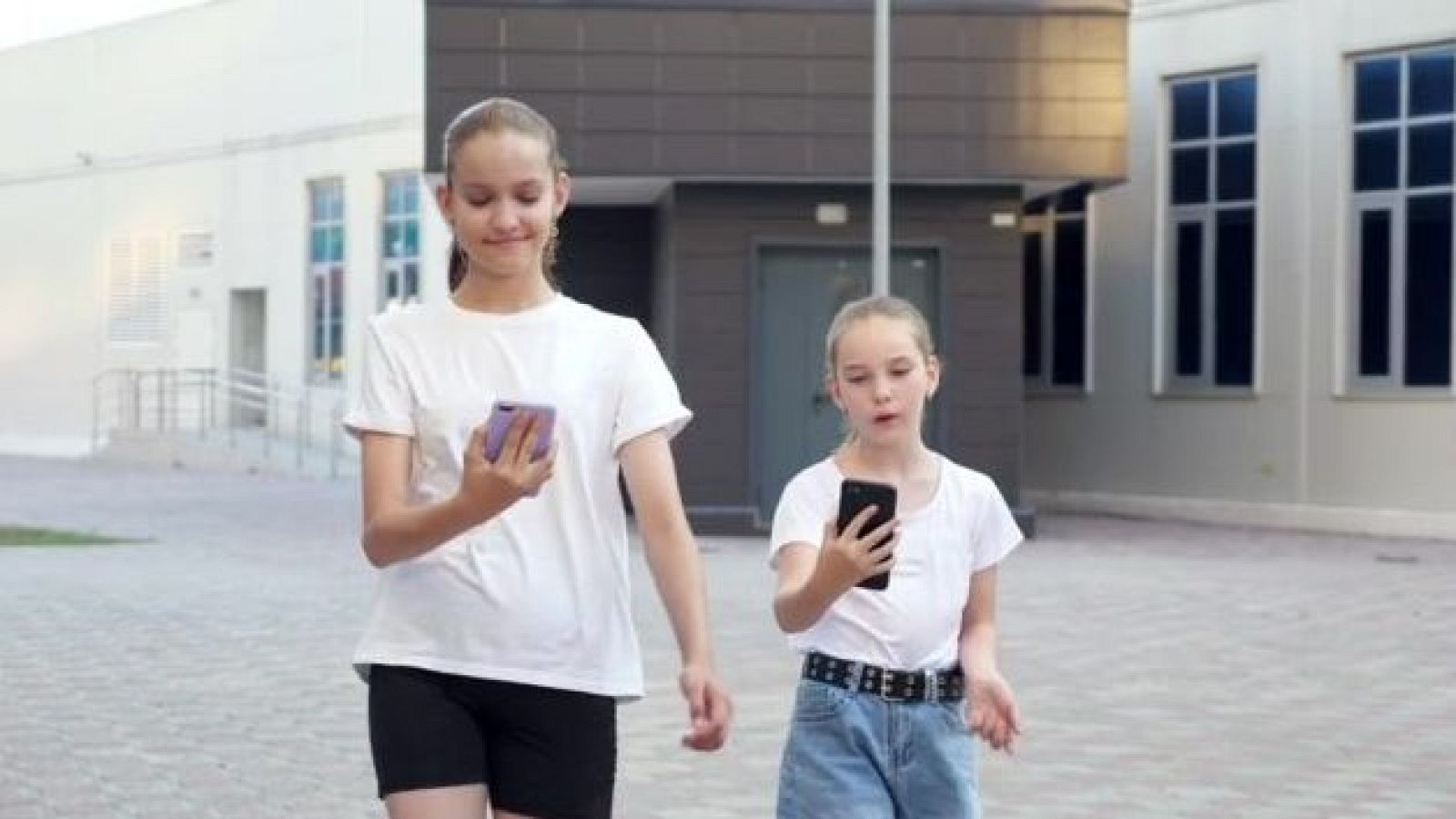 Niñas usando el móvil mientras caminan por la calle
