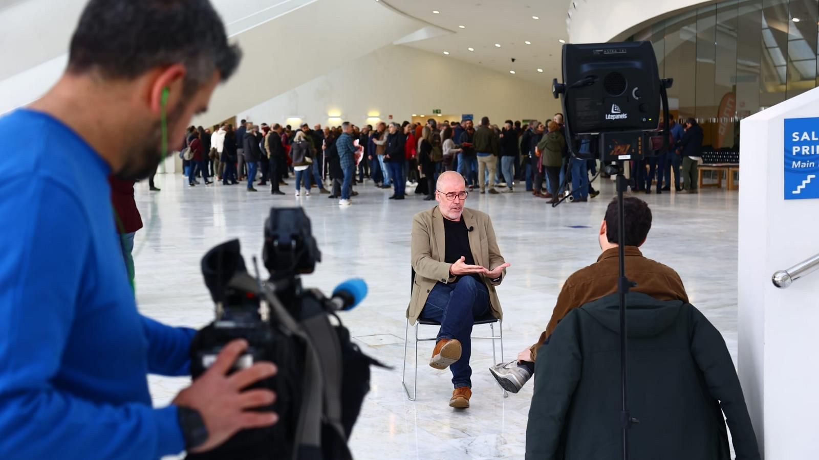 Unai Sordo es entrevistado en un espacio moderno. Un camarógrafo graba la escena, mientras que una multitud observa. Se aprecia un foco de iluminación y una señalización de "Salida Principal".