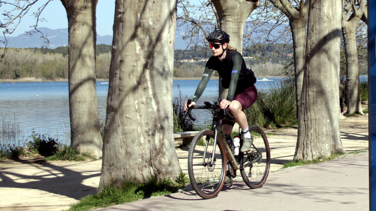 Un ciclista a punt de passar pel comptador i de fons, l'estany