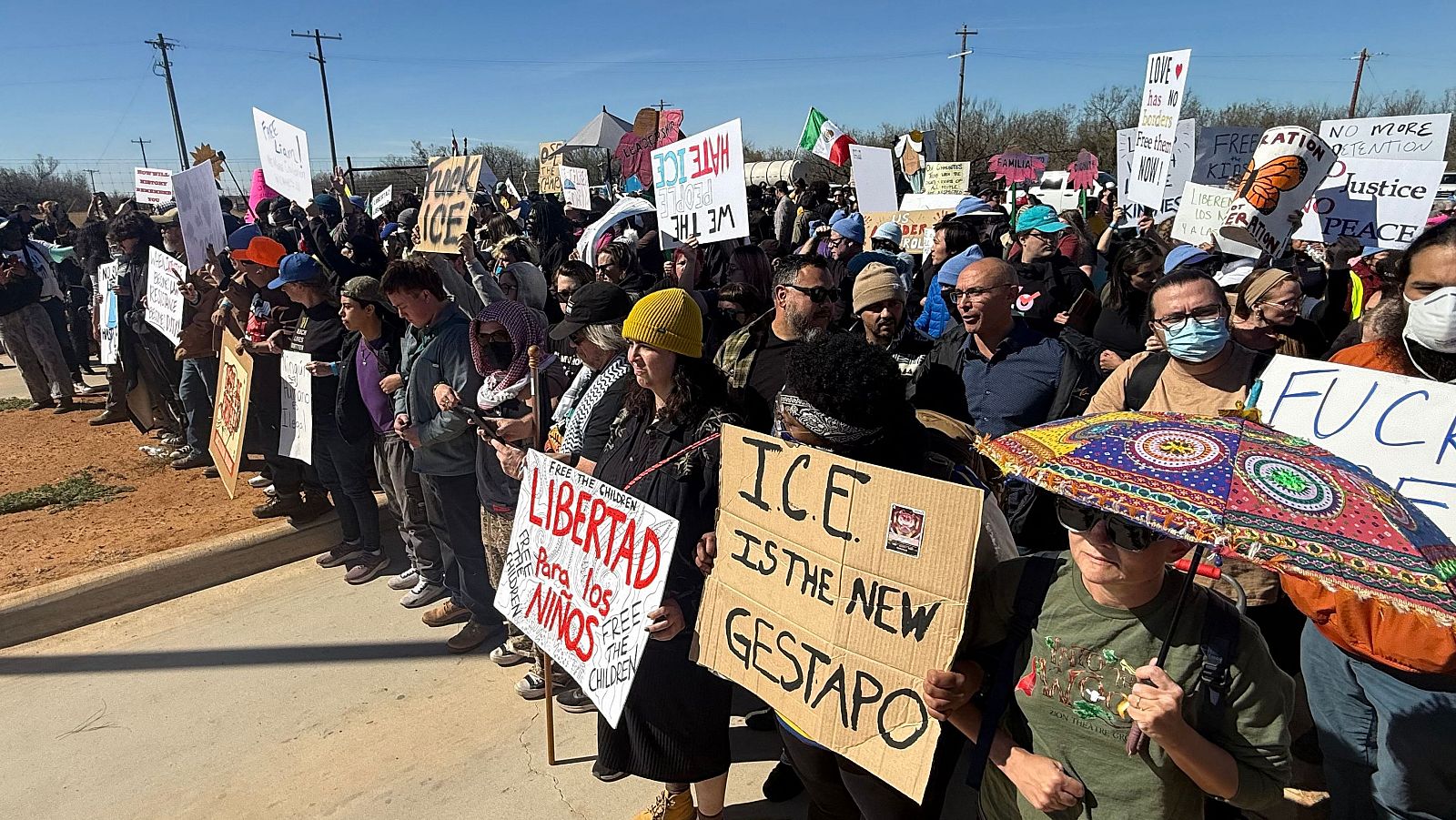 Varias personas sostienen pancartas contra ICE durante una manifestación y vigilia en protesta por la detención de niños