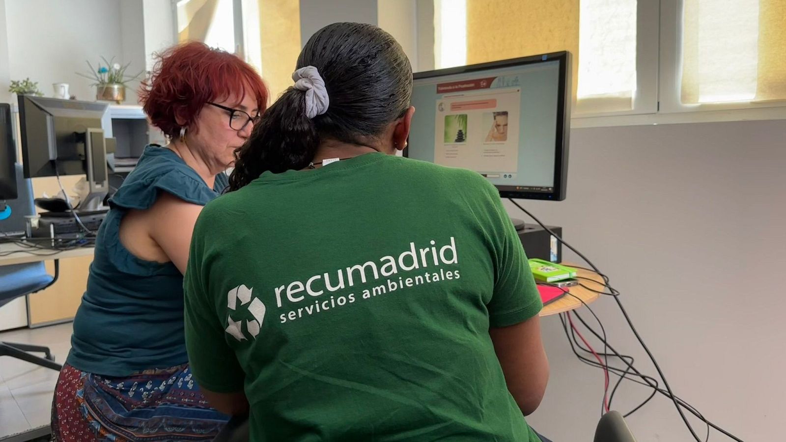 Dos mujeres trabajan frente a un ordenador en la sede de Recumadrid, empresa de inserción dedicada a la gestión de residuos.
