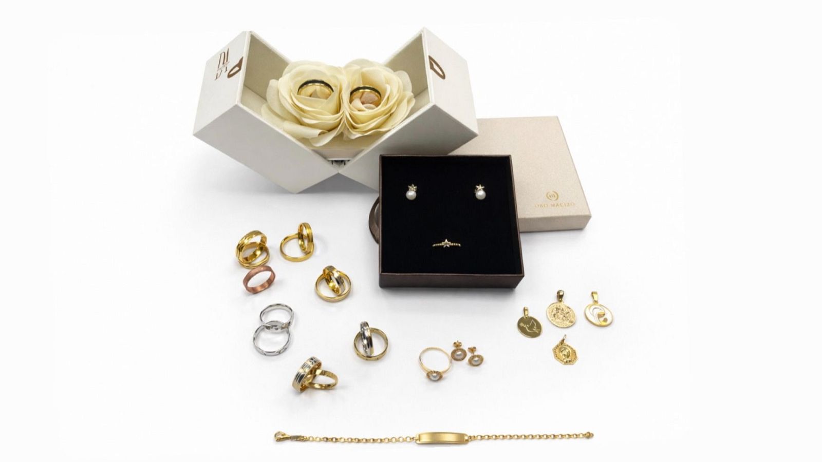 Variedad de joyas de oro macizo, oro rosa y plata: anillos, pendientes, colgantes y pulsera, dispuestas sobre fondo blanco, algunas en cajas.