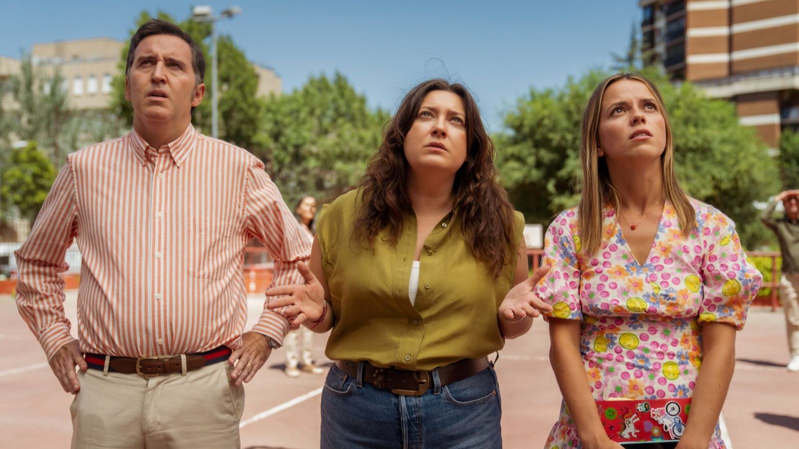 Salva Reina, María Hervás y Kira Miró miran al cielo con sorpresa. Reina con camisa a rayas, Hervás con camisa verde, y Miró con blusa colorida y objeto rojo.