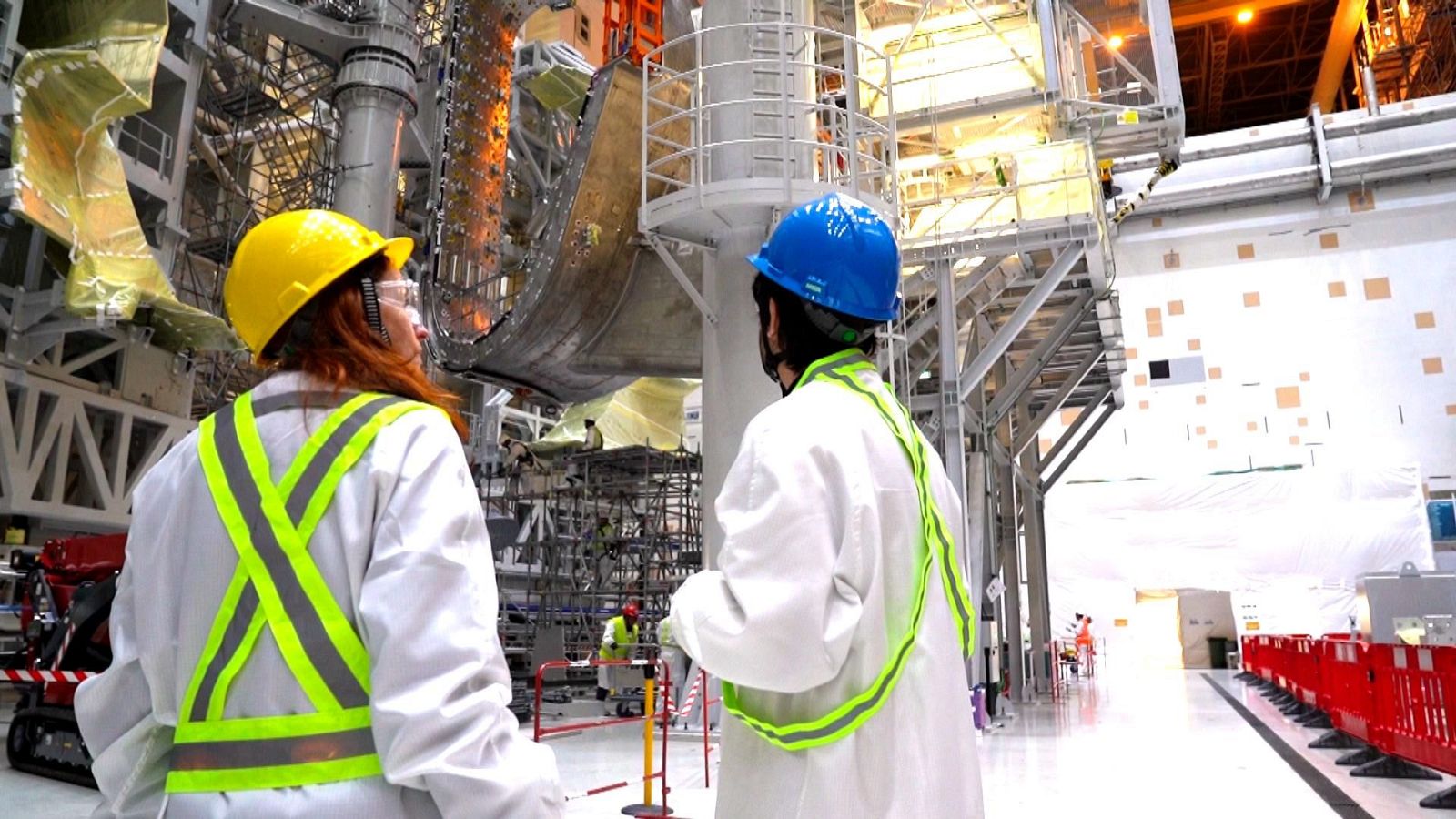 Dos personas con equipo de seguridad observan una gran estructura metálica en las instalaciones del proyecto ITER, durante una visita del programa 'El escarabajo verde'.