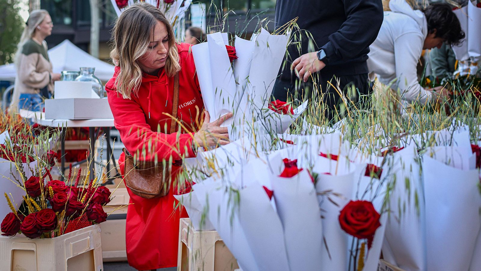 Una dona agafant dues roses en una parada a Barcelona.