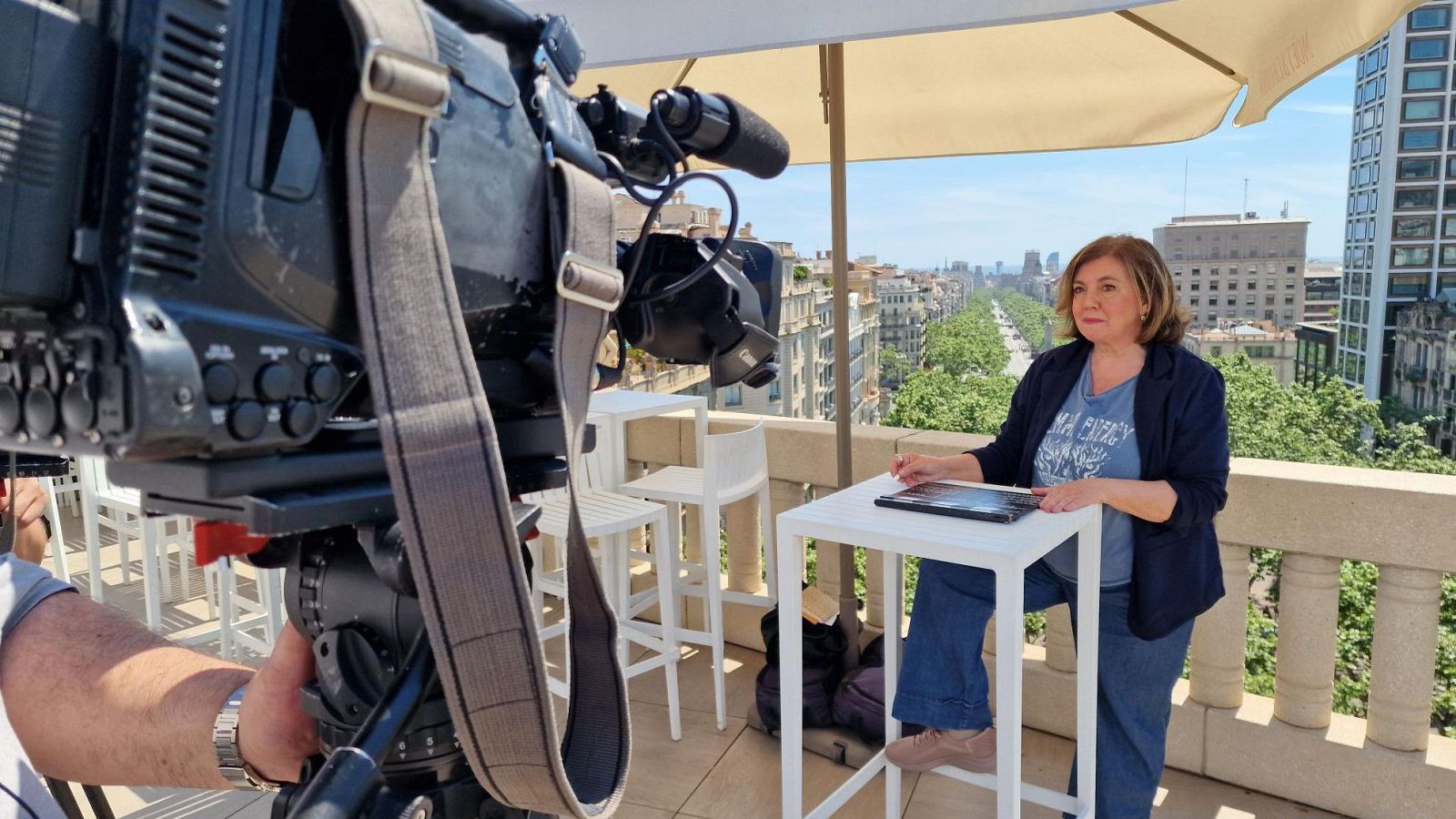 Conxita Casanovas, directora del BCN Film Fest, es grabada en una terraza de Barcelona con cámara profesional y vista urbana.