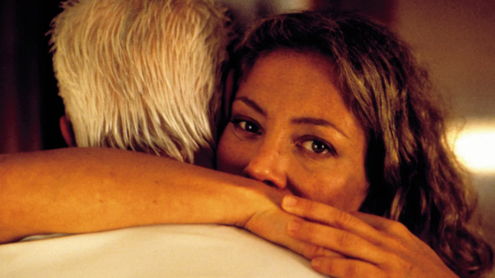 Cecilia Roth abraza a Federico Luppi en un primer plano íntimo. Roth mira a la cámara con serenidad, mientras Luppi está de espaldas. Iluminación cálida y suave.